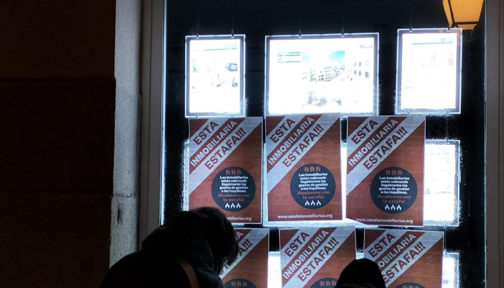 Activistas por el derecho a la vivienda pegan carteles en una sede de Tecnocasa denunciando que esta inmobiliaria está cobrando honorarios a los inquilinos, algo que la Ley de Vivienda prohíbe expresamente.